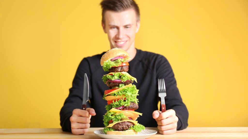 Man getting ready to eat a highly stacked hamburger