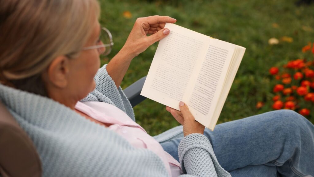 Elderly woman reading a book outdoors
